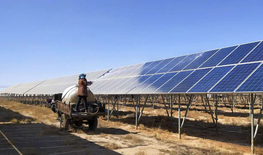 甘肃天水某光伏发电基地工人正在向被尘土覆盖的太阳能光伏发电板喷洒清洗剂